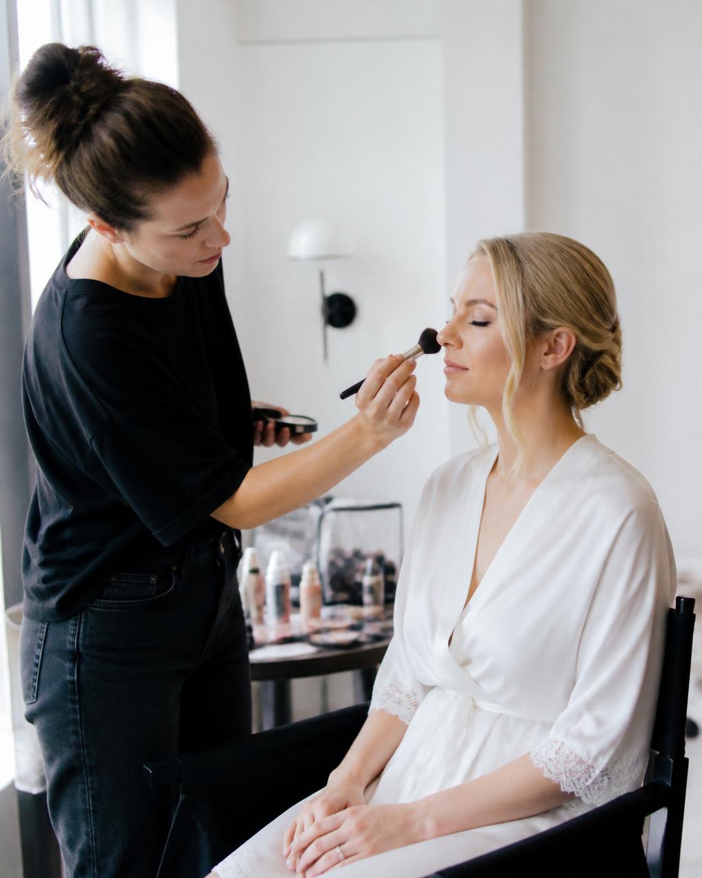 Professional makeup artist preparing a client in a bright getting-ready suite